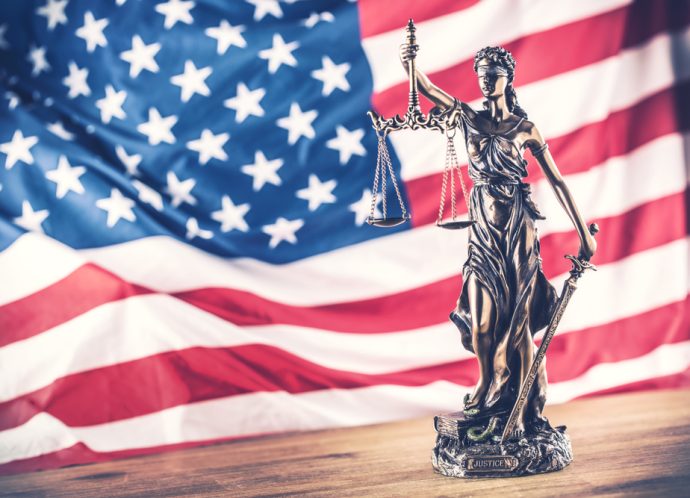 Lady,Justice,And,American,Flag,In,The,Background.